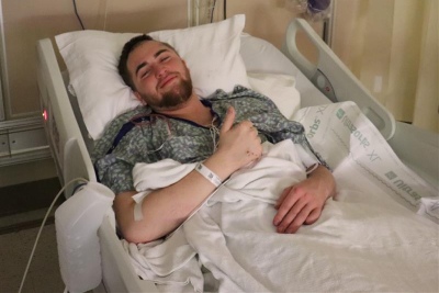 A patient giving a thumbs up from his hospital bed.